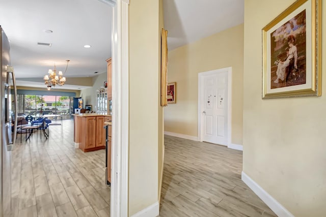 hall featuring light wood finished floors, visible vents, baseboards, a notable chandelier, and recessed lighting