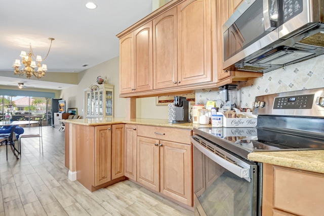 kitchen featuring stainless steel appliances, open floor plan, light brown cabinets, and a notable chandelier