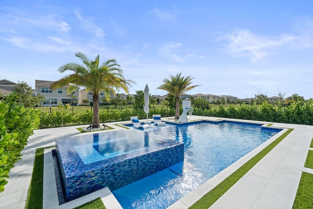 view of pool featuring a patio area, fence, and a pool with connected hot tub