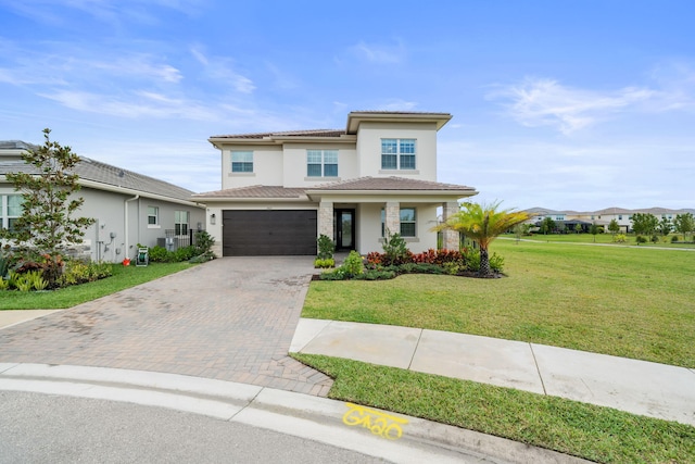 prairie-style home with an attached garage, a tiled roof, decorative driveway, stucco siding, and a front yard