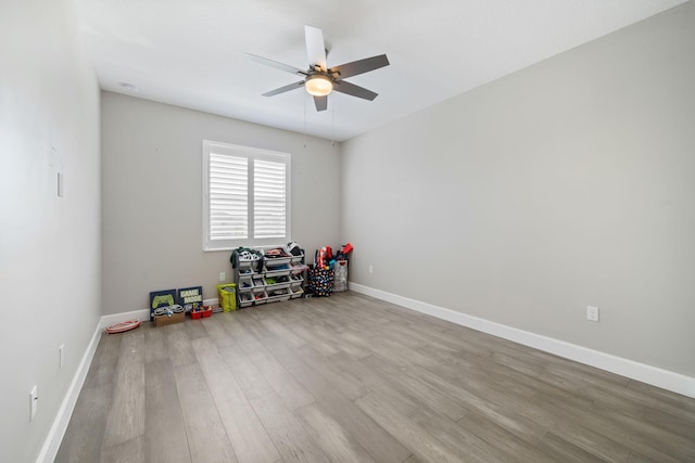interior space featuring a ceiling fan, baseboards, and light wood finished floors