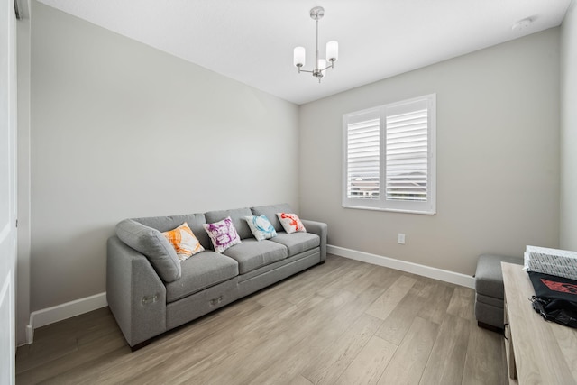 living area with light wood-style flooring, baseboards, and an inviting chandelier