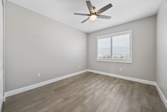 spare room featuring ceiling fan, baseboards, and wood finished floors