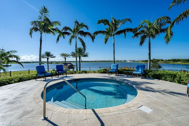 view of swimming pool featuring a water view, fence, a swimming pool, and a patio