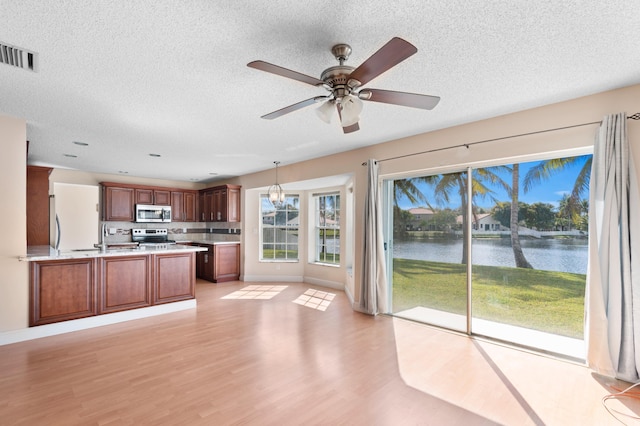 kitchen with a water view, visible vents, hanging light fixtures, appliances with stainless steel finishes, and light countertops