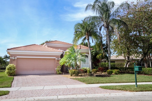 mediterranean / spanish-style home with a garage, stucco siding, a tiled roof, decorative driveway, and a front yard