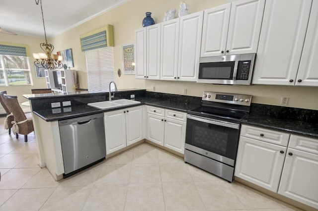 kitchen with light tile patterned floors, stainless steel appliances, a sink, white cabinets, and decorative light fixtures