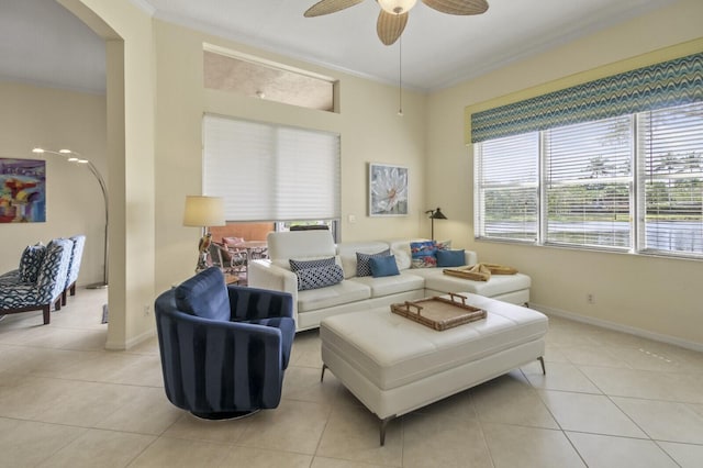 living area with ornamental molding, light tile patterned flooring, a ceiling fan, and baseboards