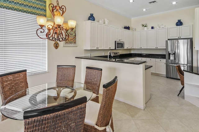 kitchen featuring a chandelier, a peninsula, white cabinets, appliances with stainless steel finishes, and dark countertops