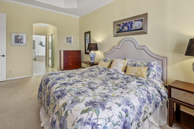 bedroom featuring baseboards, arched walkways, light colored carpet, ensuite bathroom, and crown molding