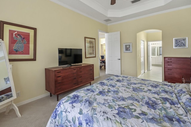 bedroom featuring light carpet, arched walkways, a ceiling fan, ornamental molding, and a tray ceiling