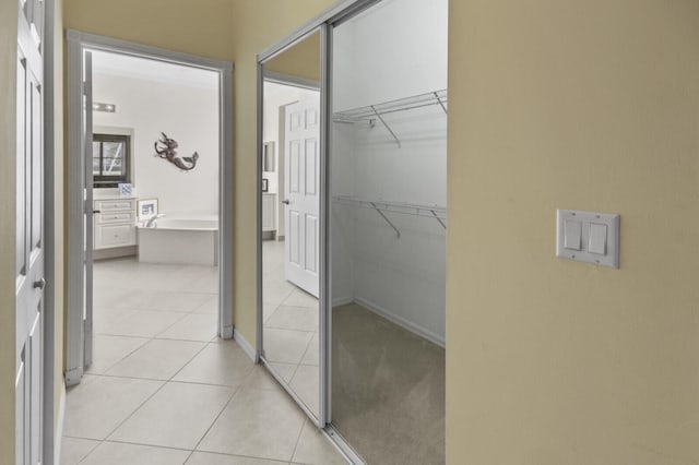 hall featuring light tile patterned floors and baseboards