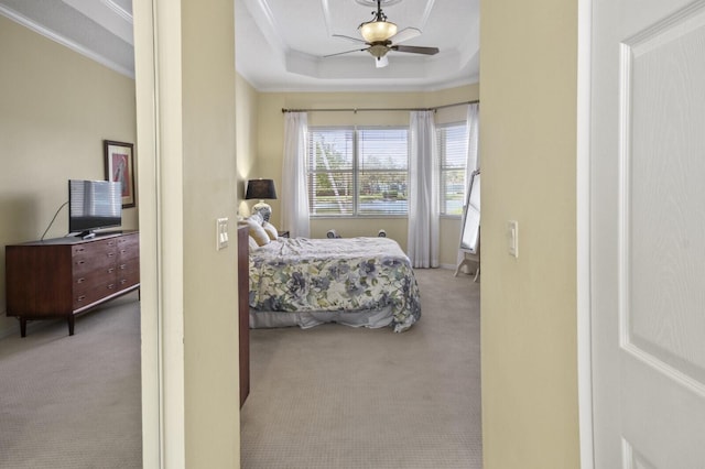 bedroom featuring ornamental molding, a raised ceiling, light carpet, and ceiling fan