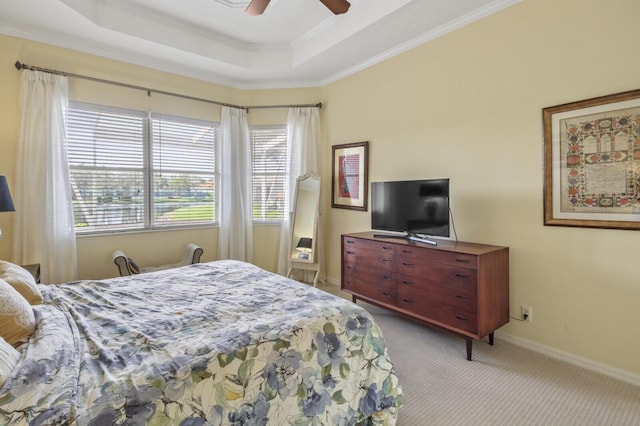 bedroom featuring baseboards, a raised ceiling, a ceiling fan, light colored carpet, and crown molding