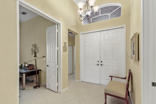 foyer entrance with light tile patterned floors, a notable chandelier, a high ceiling, visible vents, and baseboards