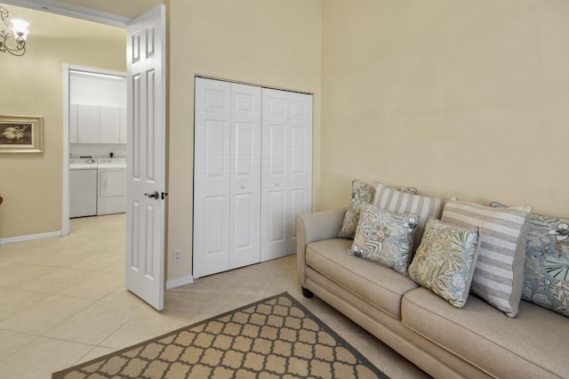 living room featuring light tile patterned floors, washer and clothes dryer, an inviting chandelier, and baseboards