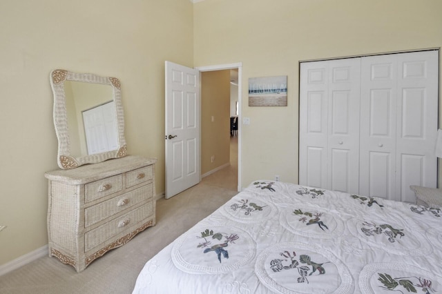 bedroom featuring baseboards, a closet, and light colored carpet