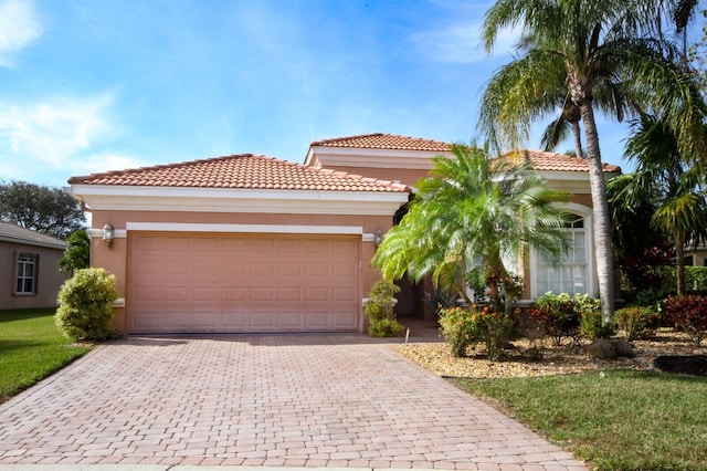 mediterranean / spanish home featuring a garage, a tile roof, decorative driveway, and stucco siding