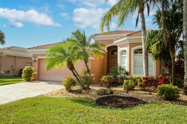 mediterranean / spanish house featuring a garage, a front lawn, decorative driveway, and stucco siding