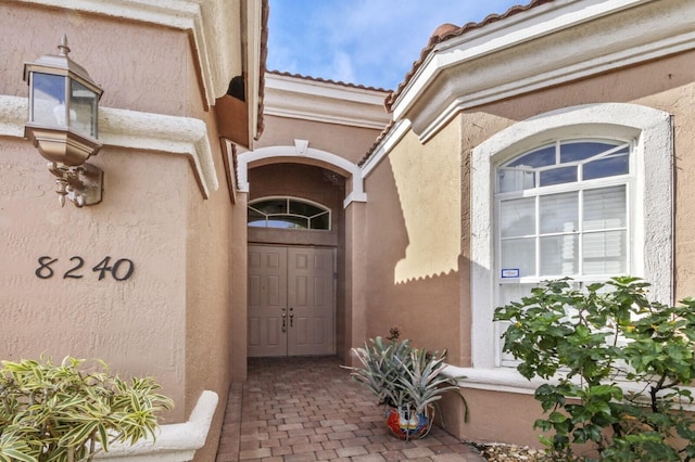 doorway to property featuring stucco siding and a tiled roof