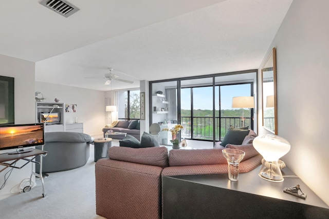 living room featuring a ceiling fan, expansive windows, visible vents, and carpet