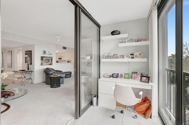 carpeted home office featuring floor to ceiling windows and ceiling fan