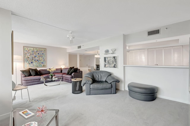 carpeted living room with a textured ceiling, visible vents, and a ceiling fan