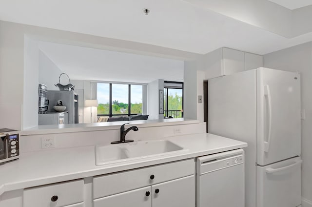 kitchen with light countertops, white appliances, a sink, and white cabinetry