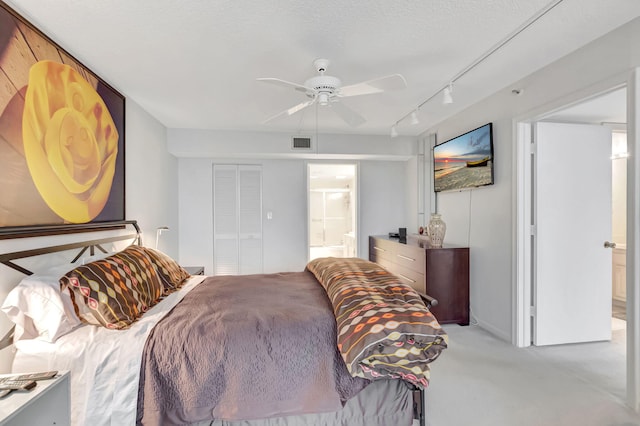 bedroom with visible vents, ensuite bathroom, light carpet, ceiling fan, and a textured ceiling