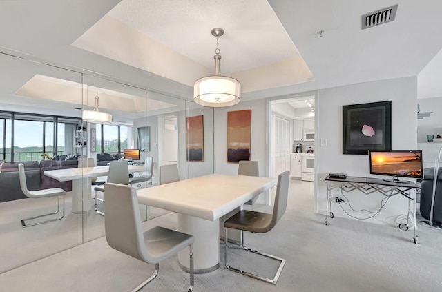 dining space featuring french doors, a tray ceiling, visible vents, and light colored carpet