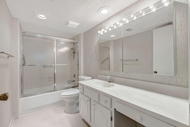 bathroom with combined bath / shower with glass door, vanity, toilet, and tile patterned floors