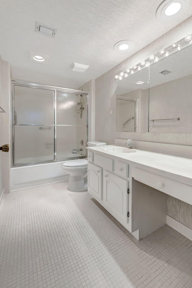 bathroom featuring toilet, tile patterned floors, bath / shower combo with glass door, and vanity