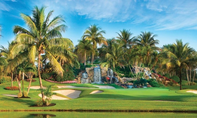 view of property's community with view of golf course and a yard