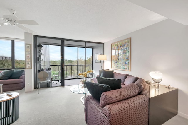 living area featuring ceiling fan, baseboards, a wall of windows, and carpet flooring