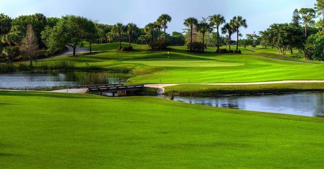 view of community featuring a water view, a yard, and golf course view