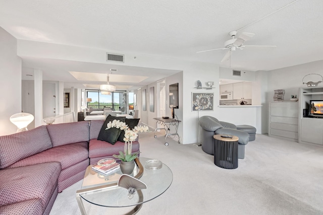 living room featuring ceiling fan, visible vents, and light colored carpet