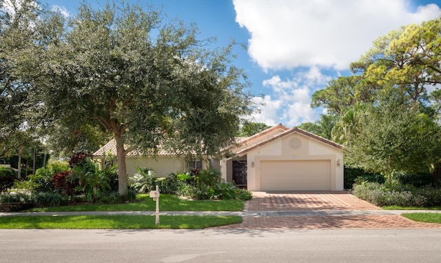 view of front of property with a garage, decorative driveway, a tile roof, and stucco siding