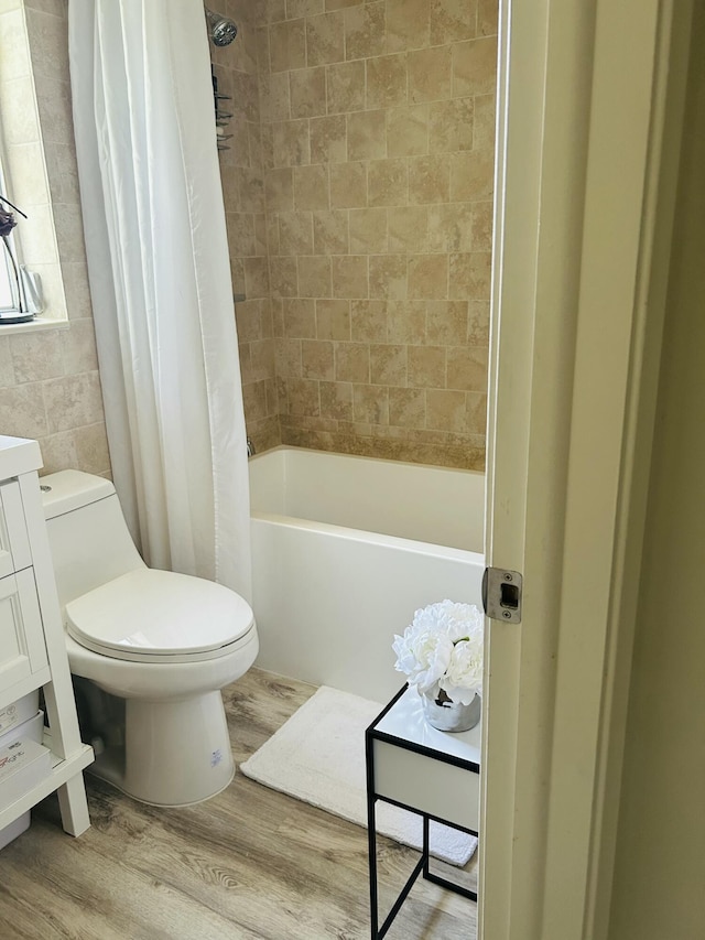 full bath with tile walls, shower / bath combination with curtain, toilet, vanity, and wood finished floors