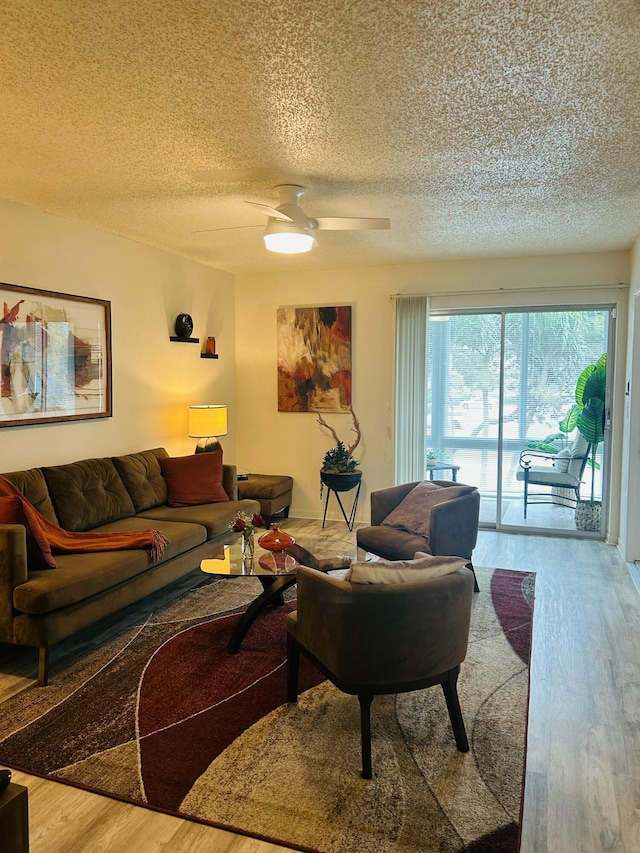 living room featuring ceiling fan, a textured ceiling, and wood finished floors