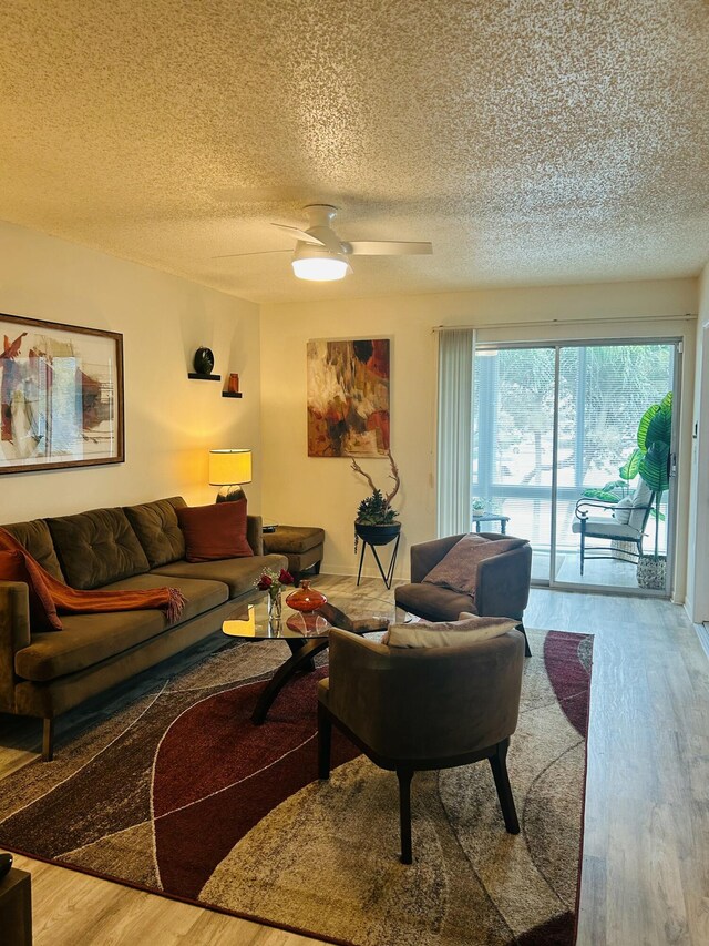 living room featuring a ceiling fan, a textured ceiling, and wood finished floors