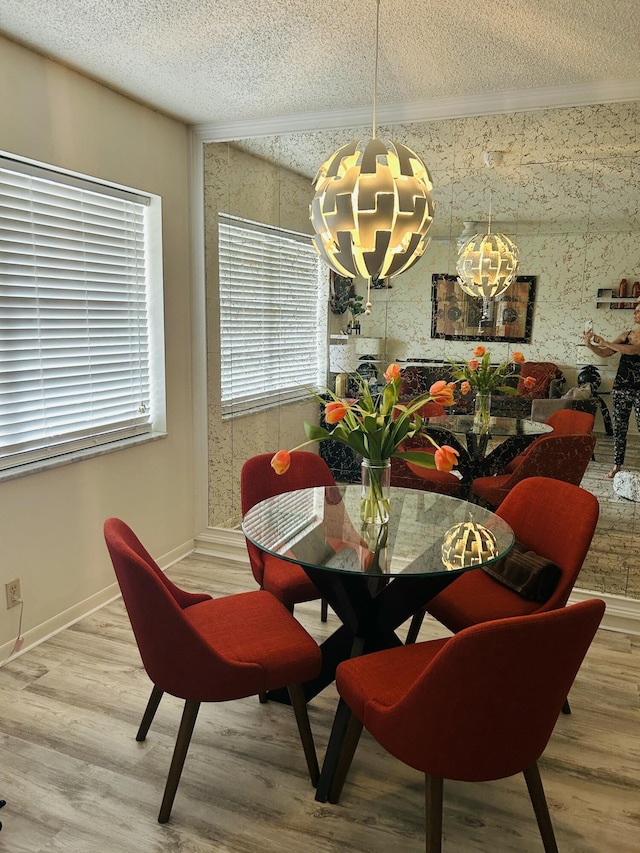 dining space featuring baseboards, wood finished floors, an inviting chandelier, crown molding, and a textured ceiling