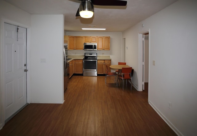kitchen with dark wood finished floors, stainless steel appliances, light countertops, light brown cabinetry, and baseboards