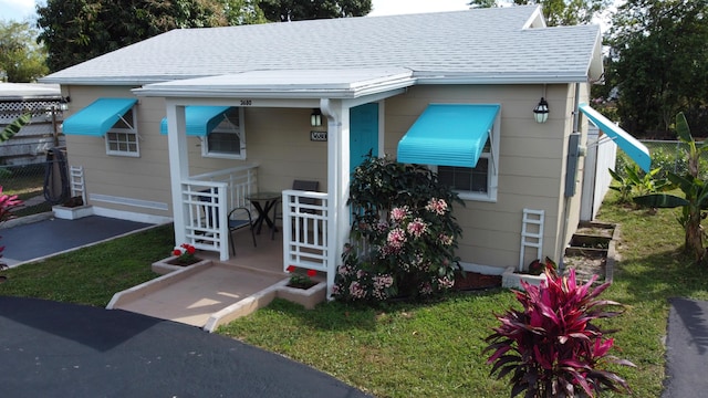 bungalow-style home featuring roof with shingles and a front yard