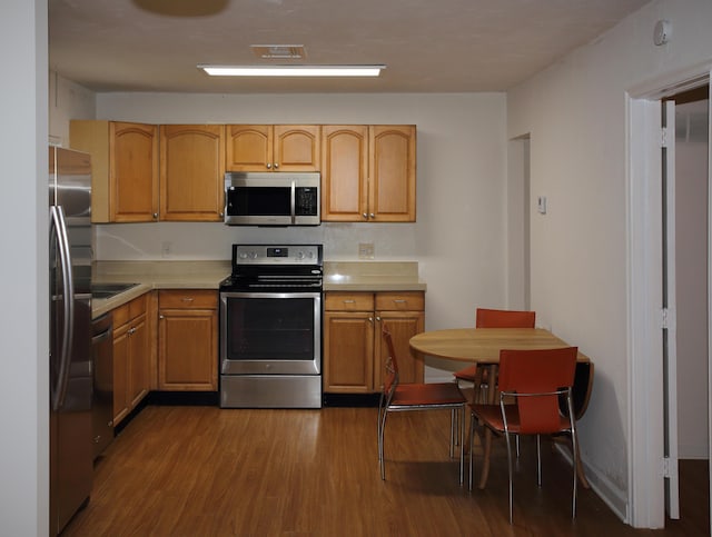 kitchen with stainless steel appliances, light countertops, visible vents, and wood finished floors