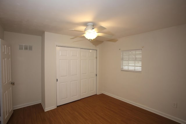 unfurnished bedroom featuring baseboards, visible vents, a ceiling fan, dark wood finished floors, and a closet