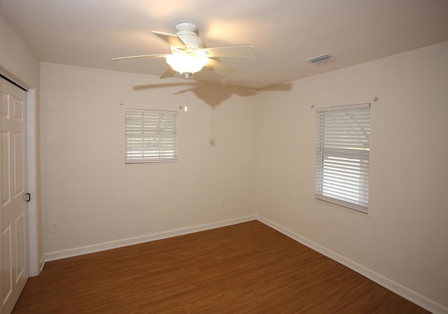 spare room with dark wood-style floors, baseboards, visible vents, and a ceiling fan