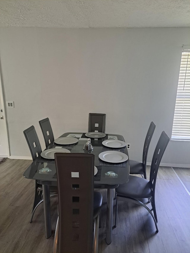 dining room featuring dark wood-style flooring, a textured ceiling, and baseboards