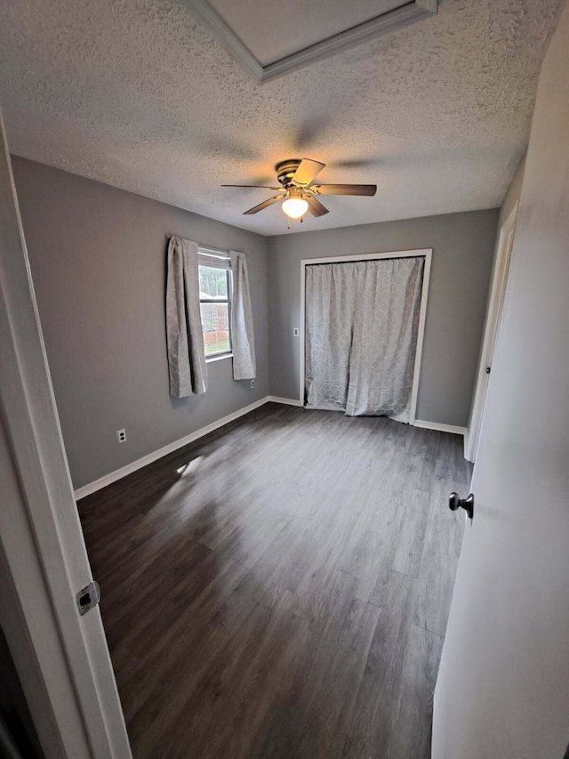 unfurnished bedroom with dark wood-style floors, ceiling fan, a textured ceiling, and baseboards