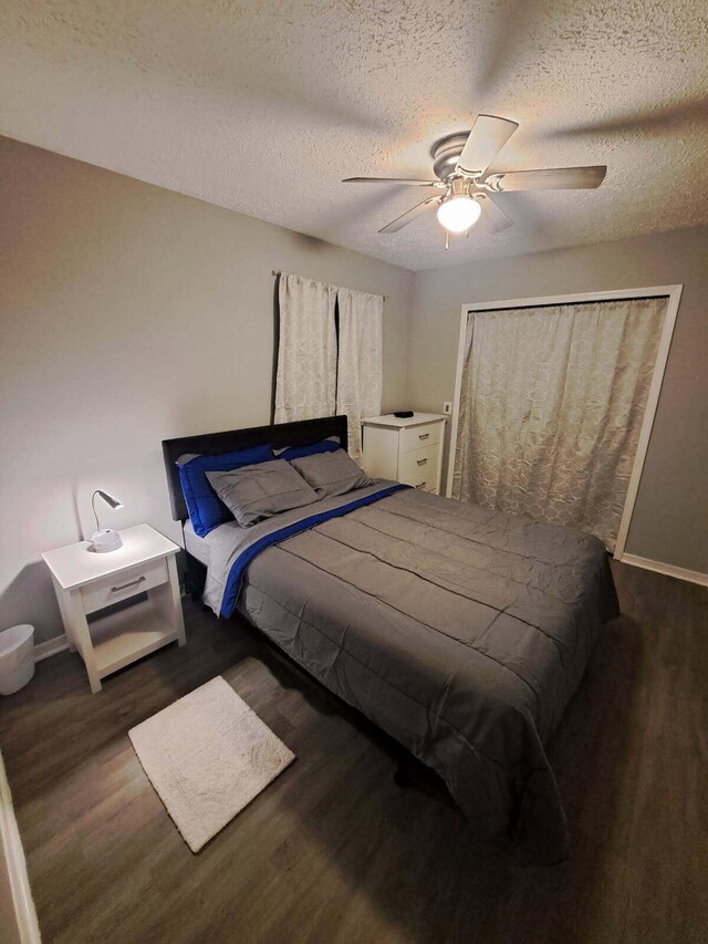 bedroom featuring dark wood-style flooring, a textured ceiling, and baseboards