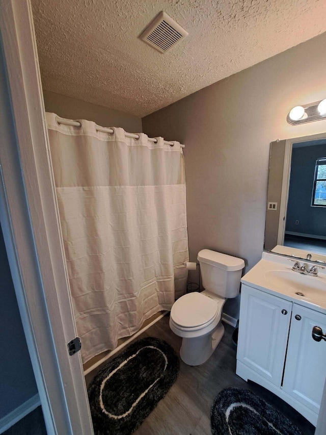 bathroom featuring visible vents, toilet, wood finished floors, a textured ceiling, and vanity